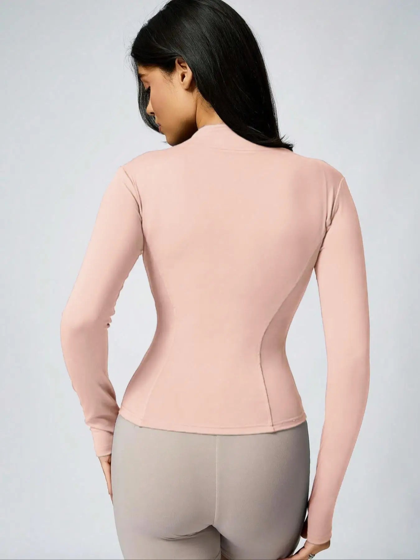 Woman in brown cropped athletic jacket, beige sports bra, and biker shorts