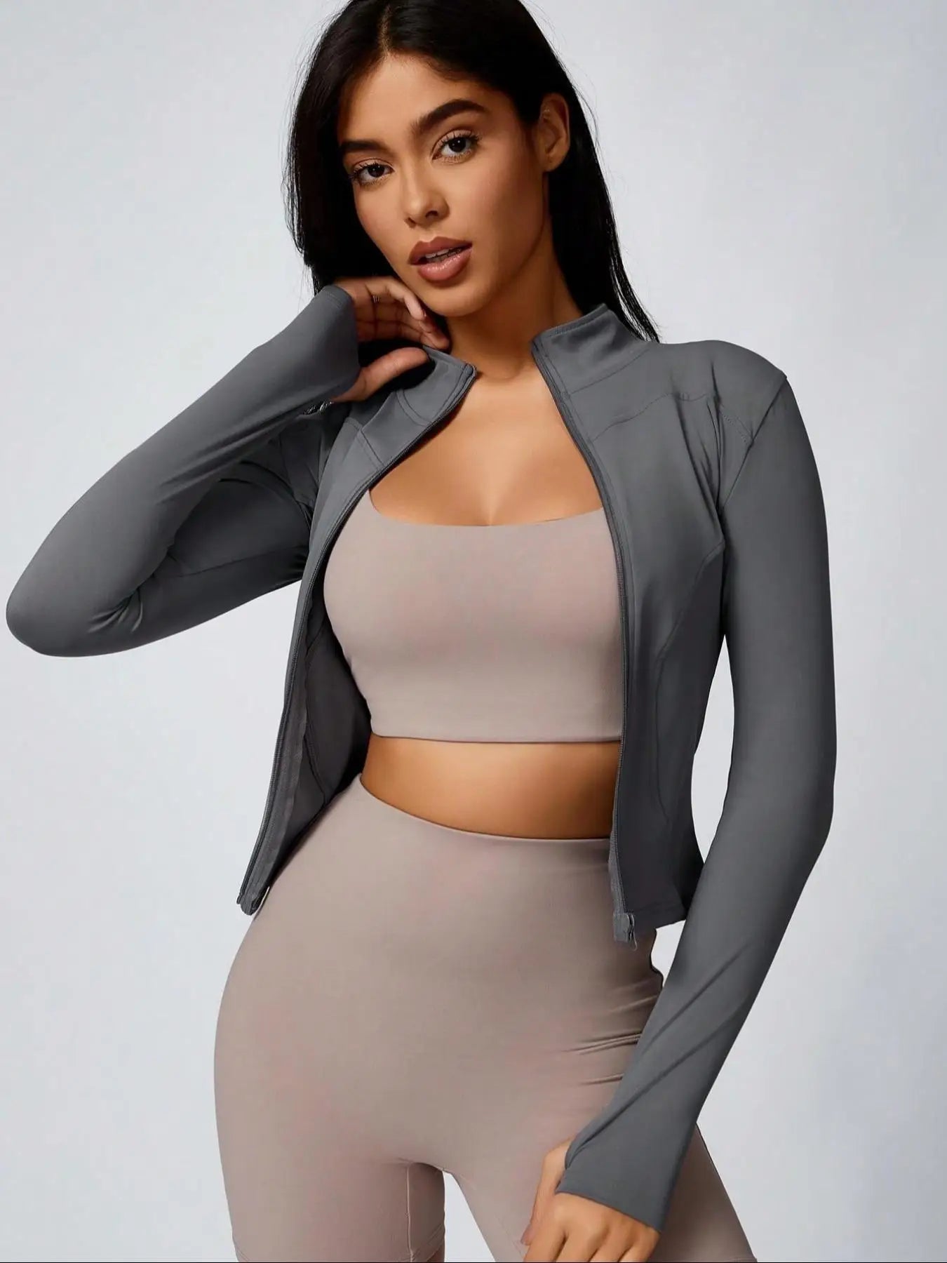 Brown cropped athletic jacket over beige sports bra and biker shorts