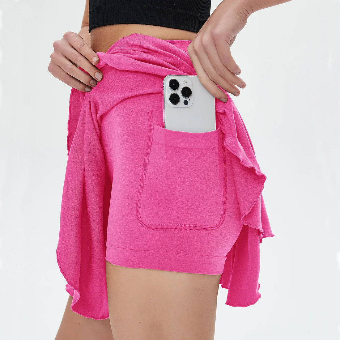 White high waisted tennis mini skirt with side pocket holding smartphone