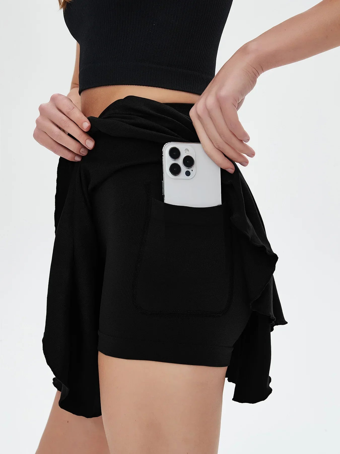 High waisted tennis mini skirt with side pocket holding white smartphone