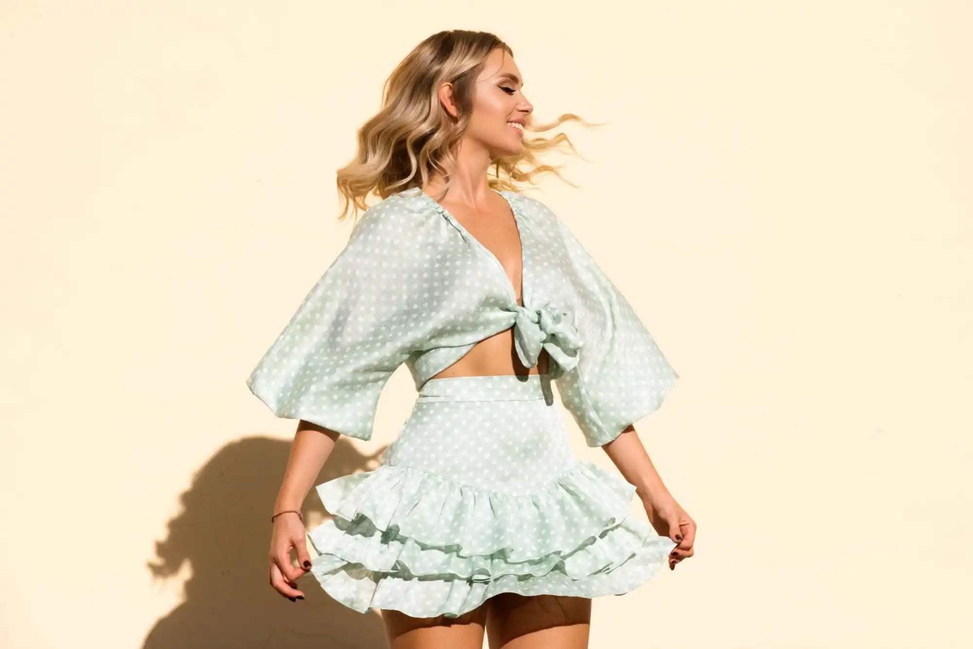 A light green polka dot two-piece set featuring a tied crop top with wide sleeves and a tiered ruffle mini skirt.slider_item_8GB7bW