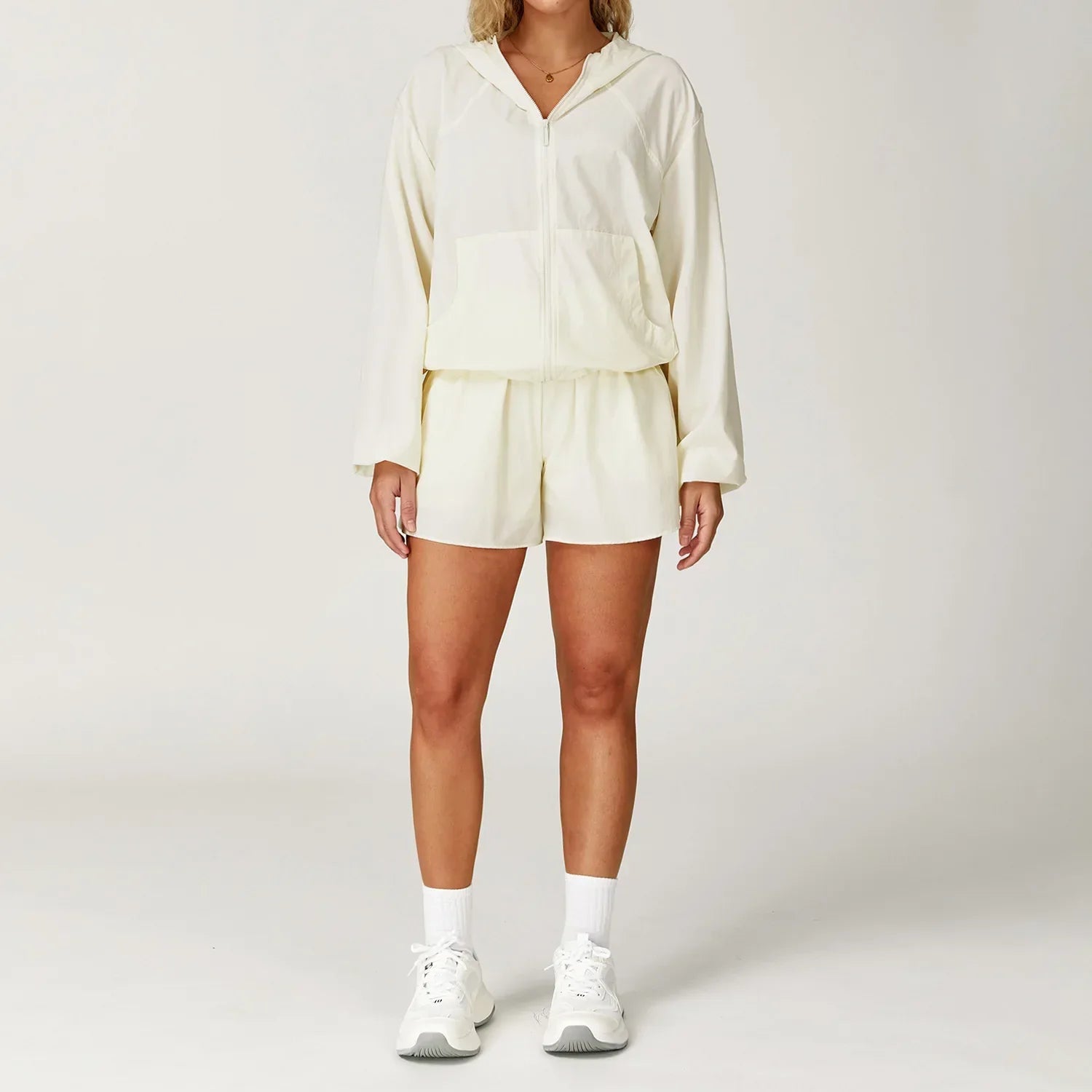 Woman in cream hooded jacket and shorts, gym lightweight windbreaker dress